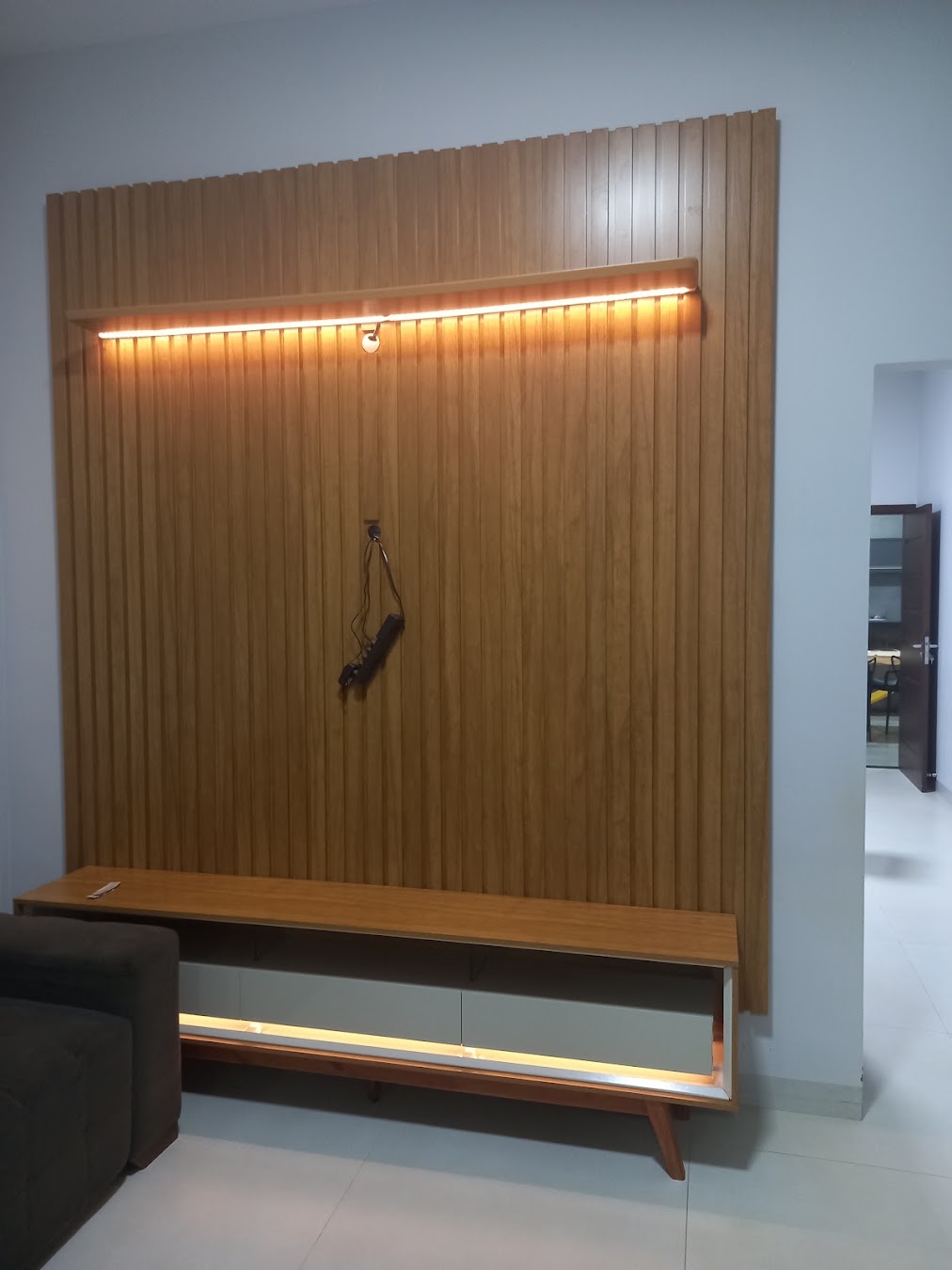Painel ripado para TV com iluminação e rack suspenso. Trabalho realizado por Daniel Monta Móveis em Goiás.